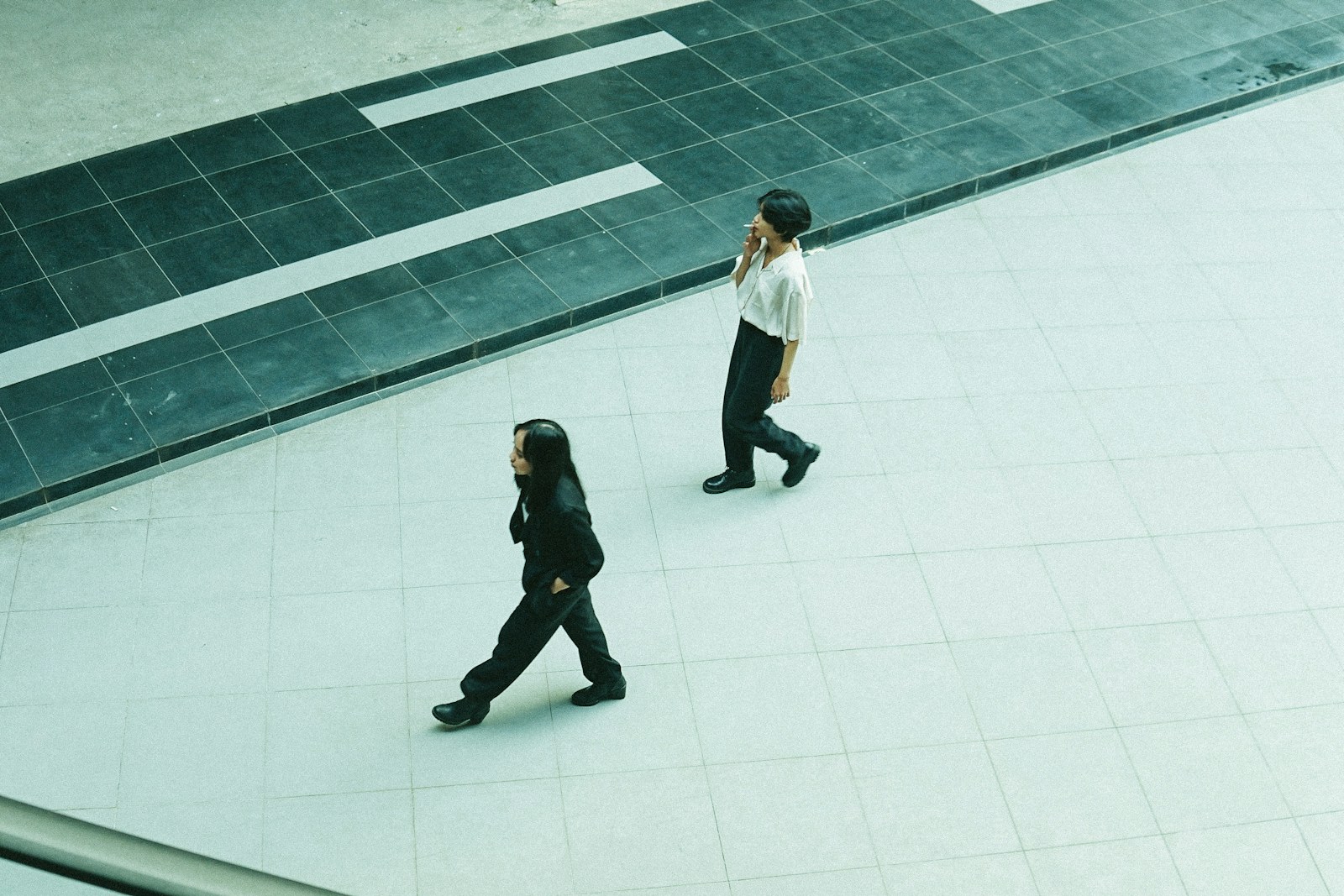 man in white shirt and black pants walking on white floor tiles
