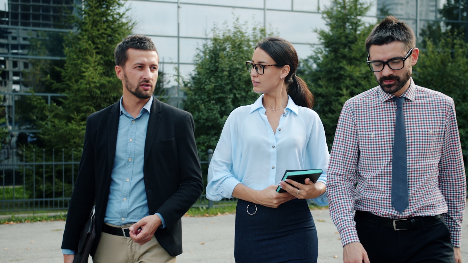 Three business people walking outside an office building
