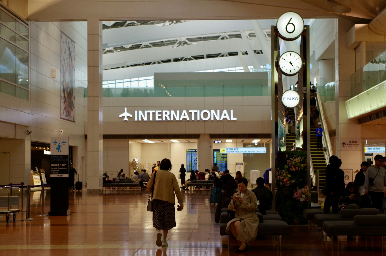 People in a modern airport terminal with large clocks