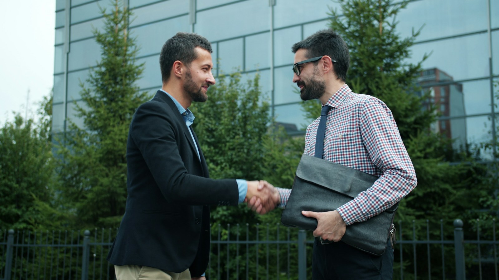 Two businessmen shaking hands outside modern building