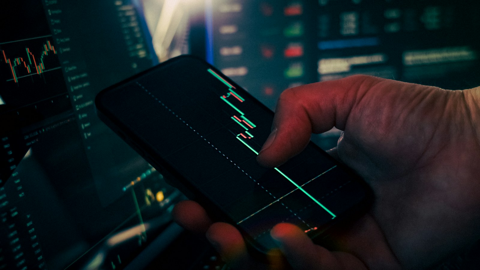 Trader analyzing stock market data on smartphone and phone