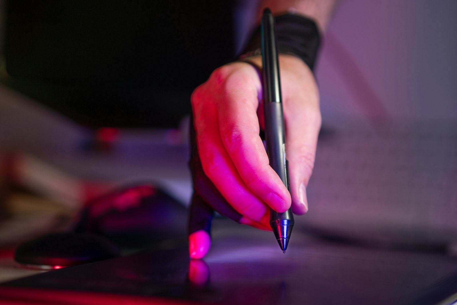 A person holding a pen and writing on a laptop
