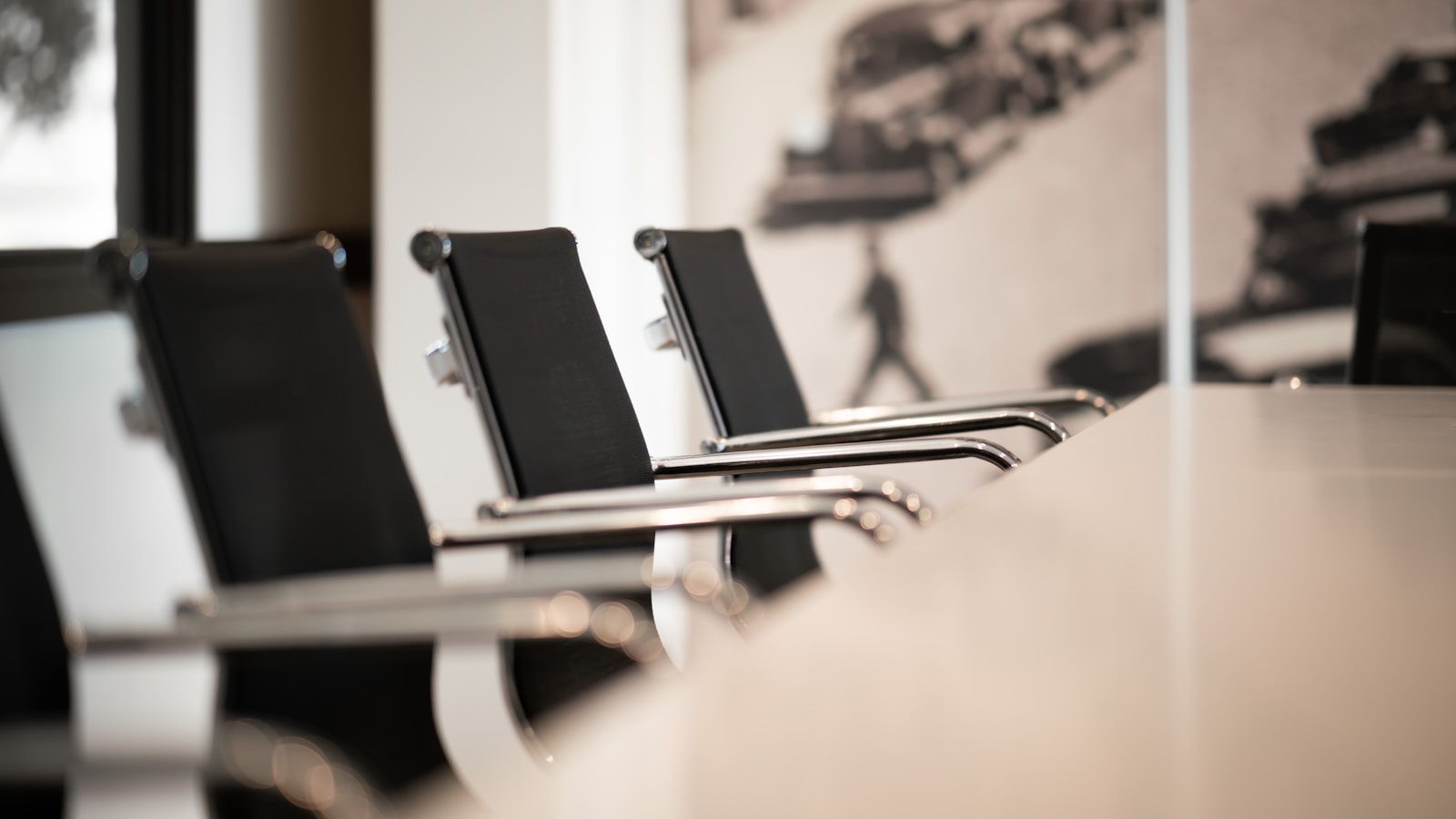 Black office chairs with chrome arms in a row at a conference table