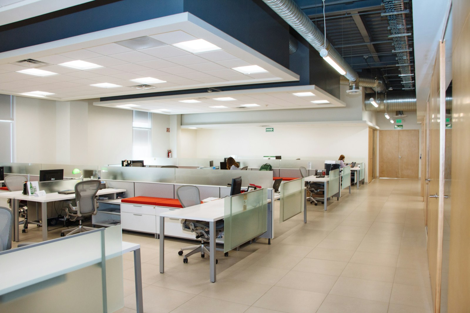 An open plan office with rows of white desks and frosted glass partitions