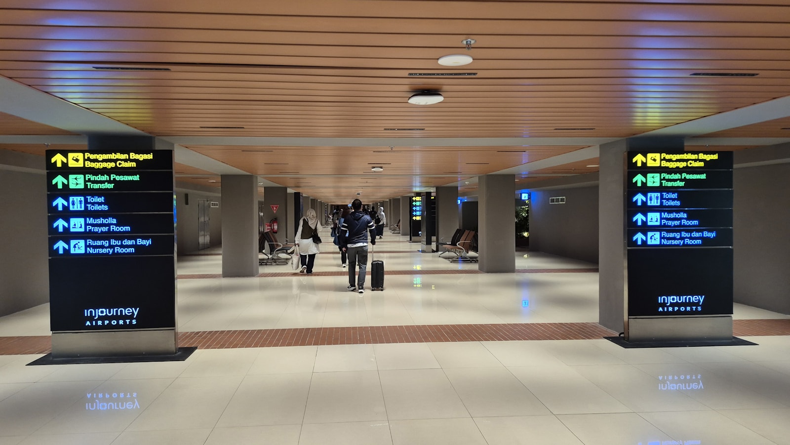 People walking through a modern airport terminal with directional signs