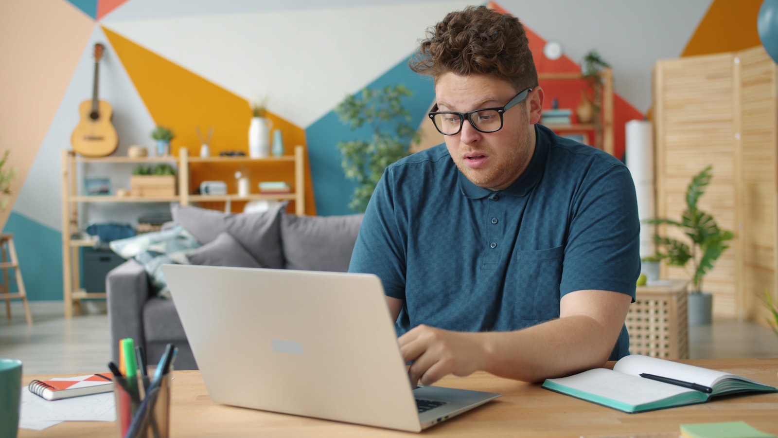 Man with glasses working on laptop at desk