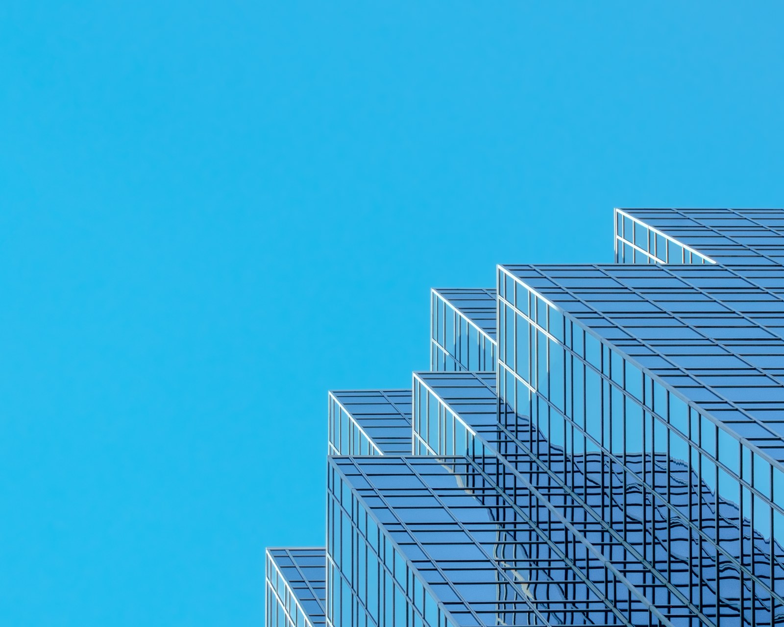 A modern glass skyscraper with a stepped facade against a clear blue sky