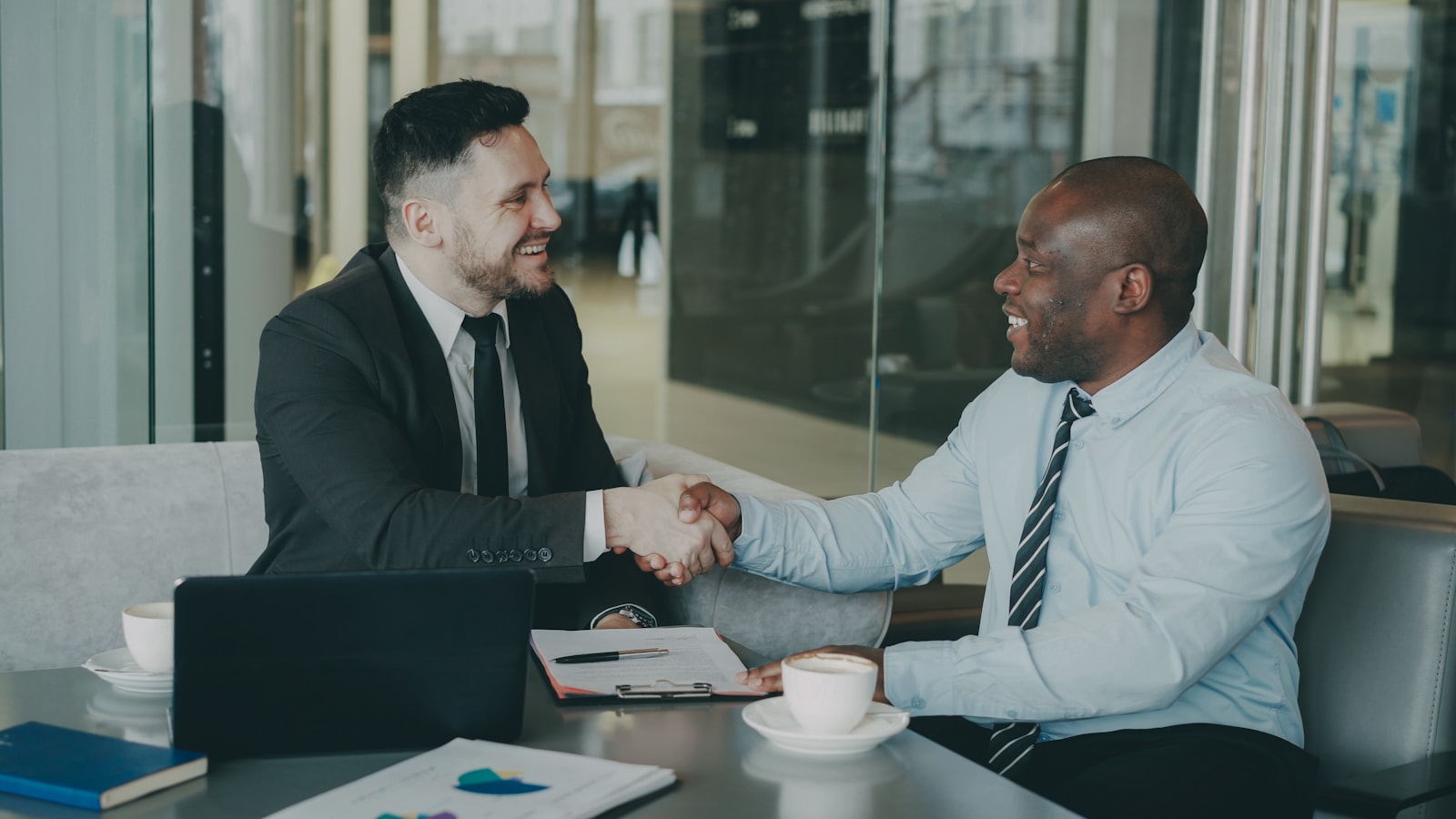Two businessmen shaking hands across a table