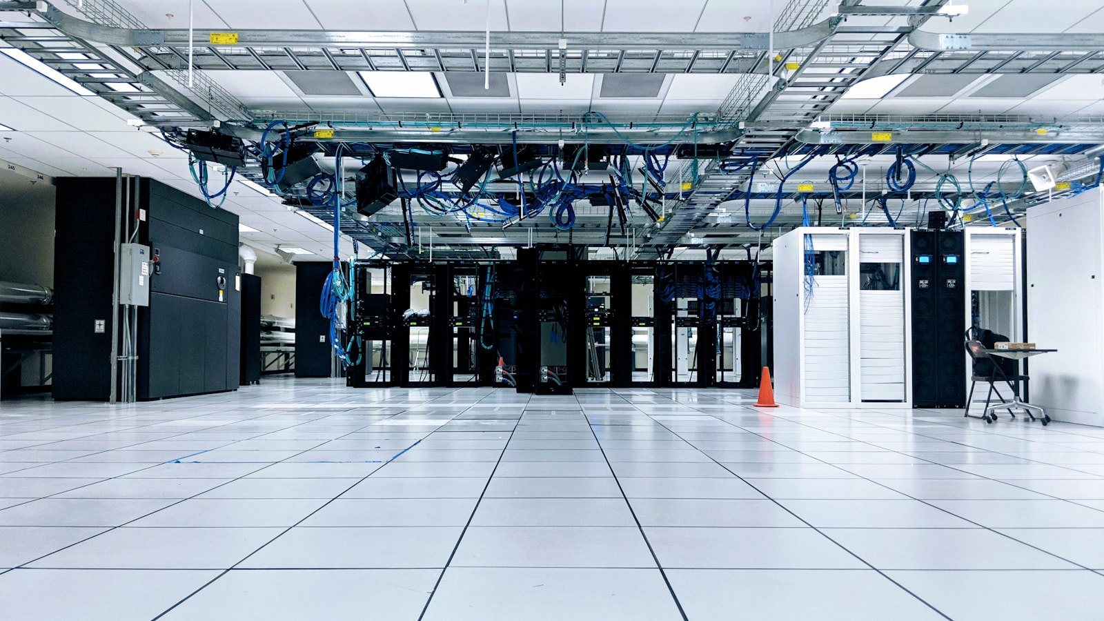 A server room with rows of black and white cabinets under blue cables