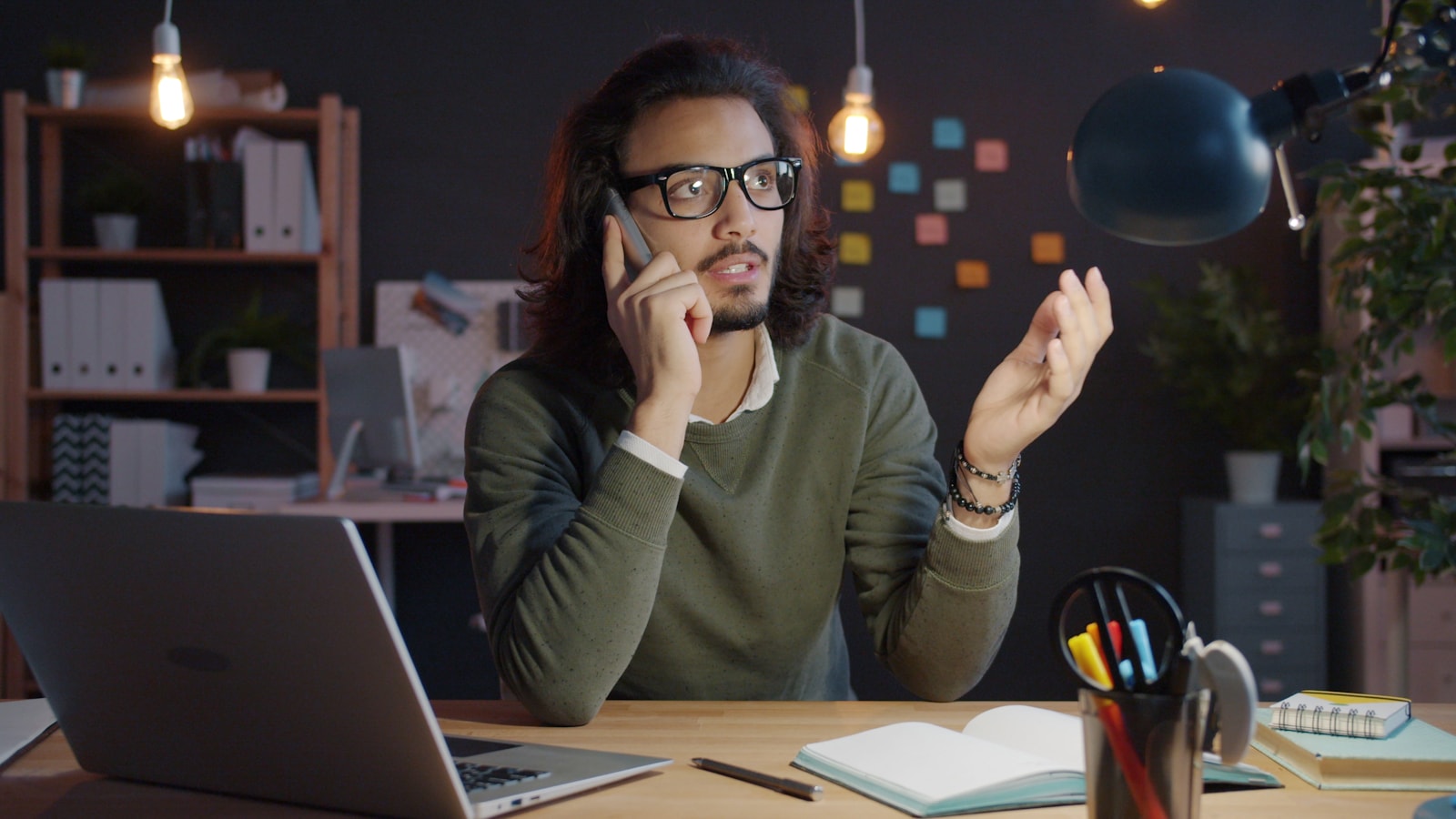Man talking on phone at desk with laptop
