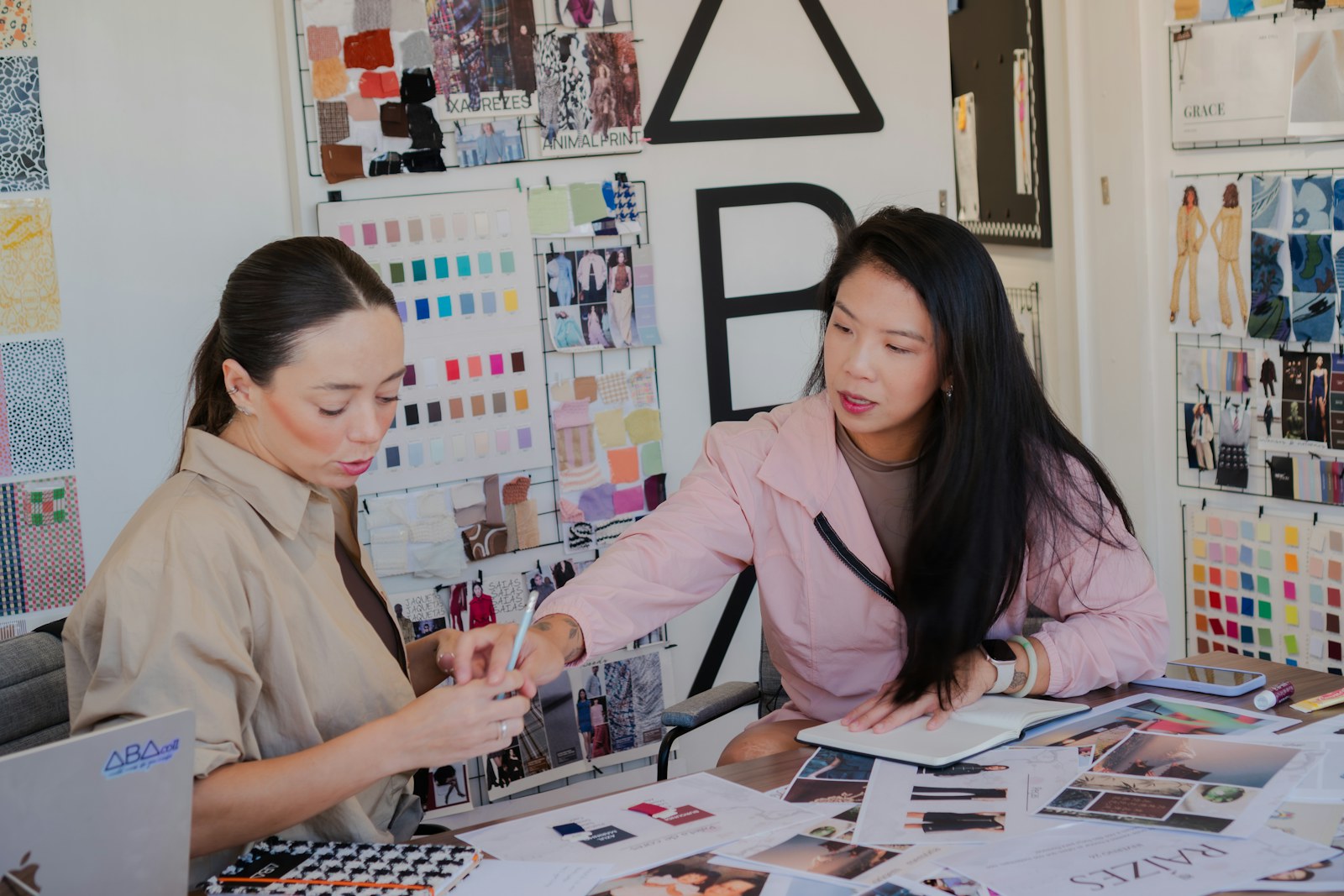 Two women collaborating at a desk with fabric swatches