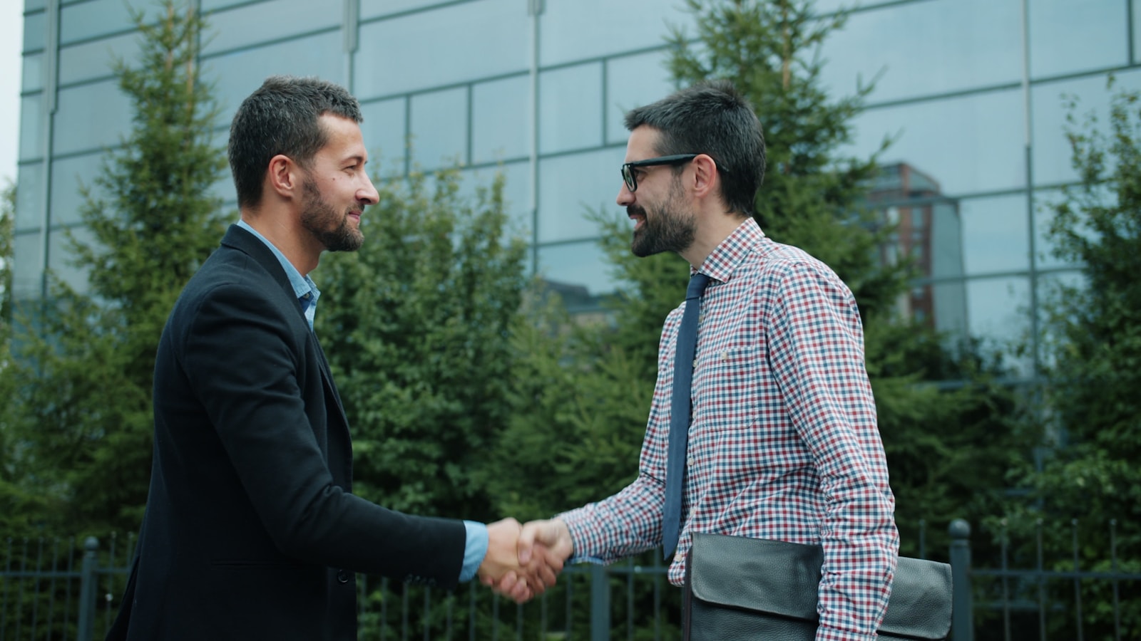 Two businessmen shaking hands outside an office building