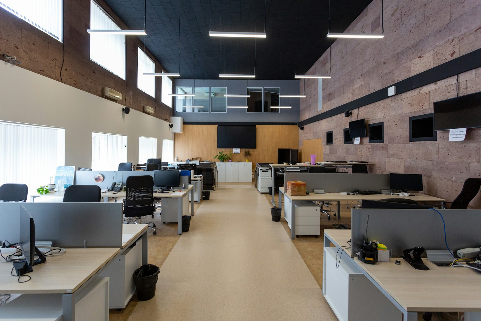 An open plan office with rows of desks and computers under linear lights