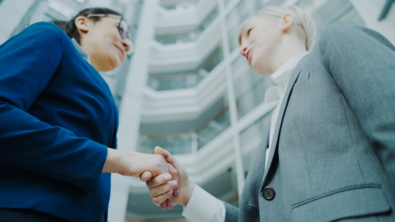 Two businesswomen shaking hands in a modern office building