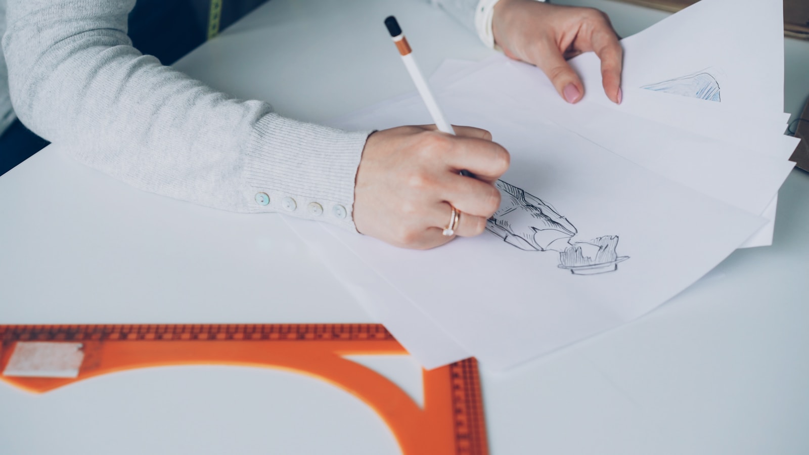 Someone is sketching a design on paper
