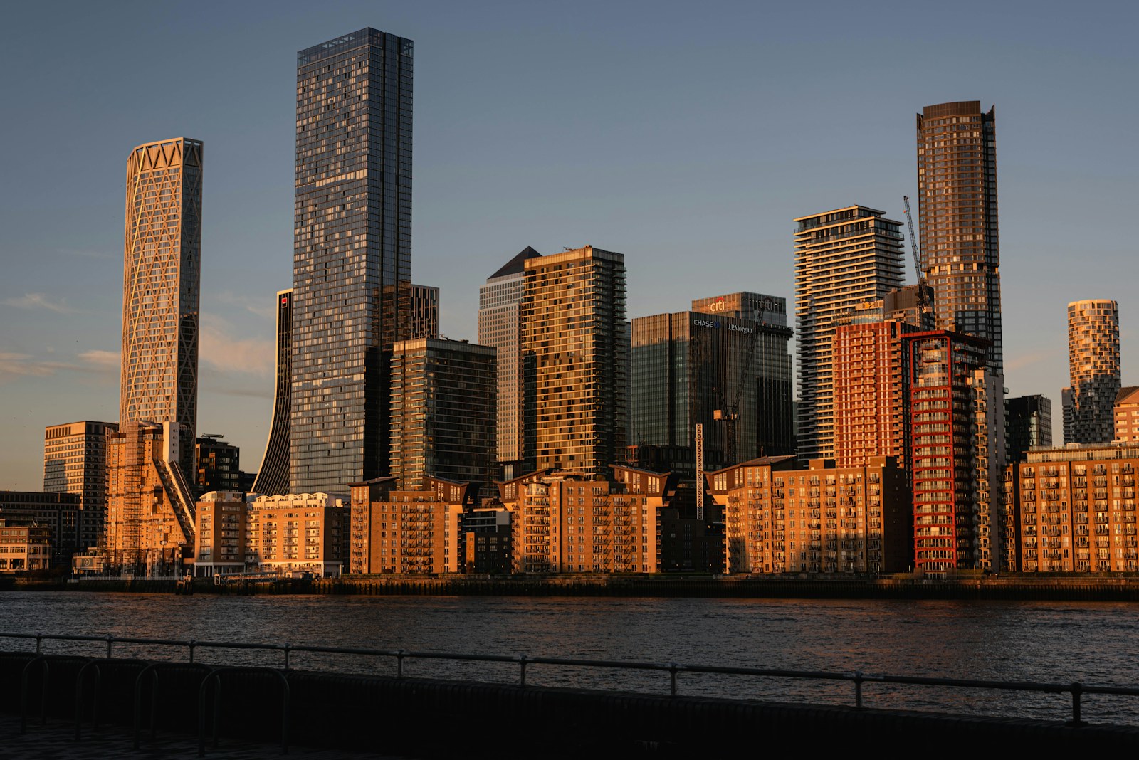 Modern city skyline with skyscrapers reflecting warm sunlight over water