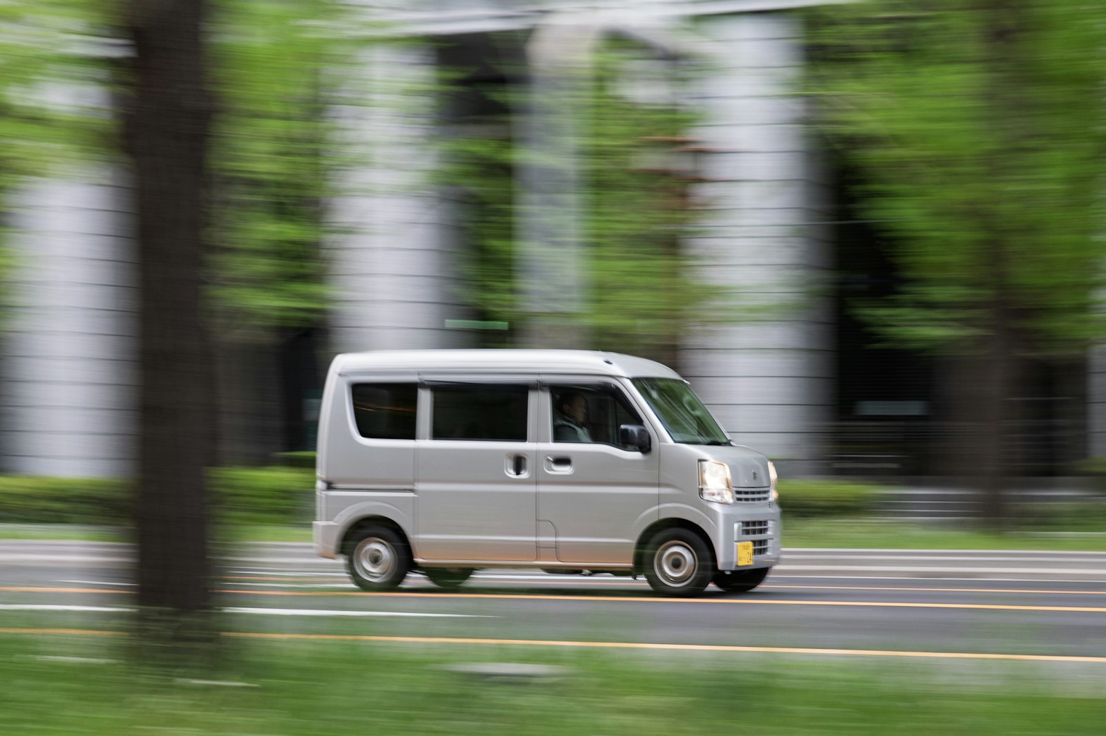 A silver van drives down a blurred street