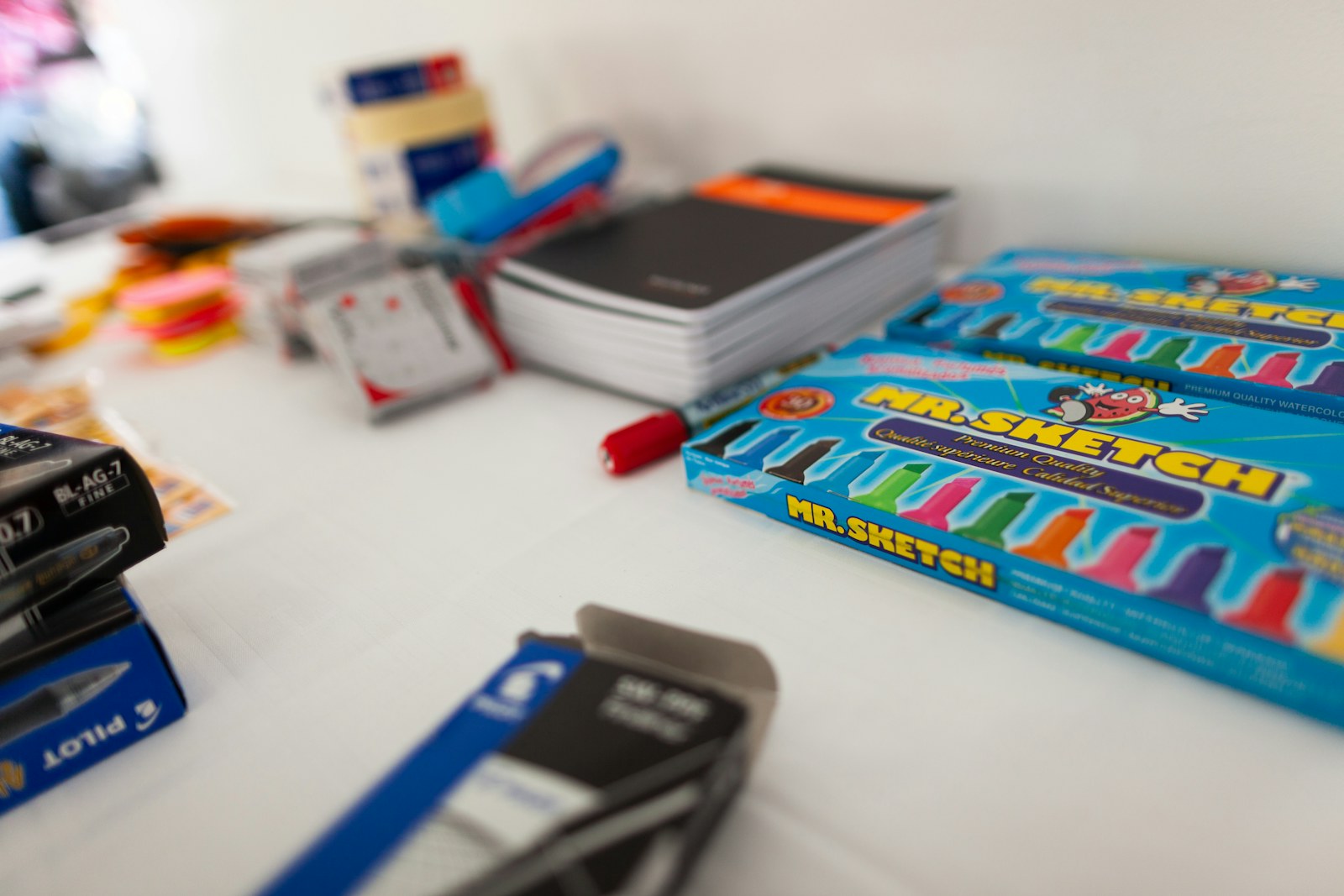 Boxes of colorful markers and notebooks on a white surface