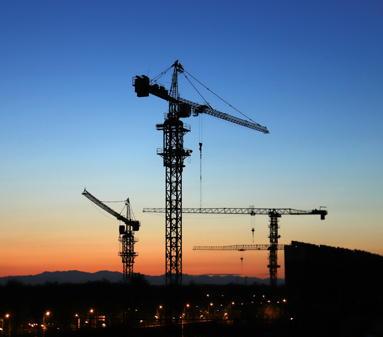 building site with tower cranes during golden hour