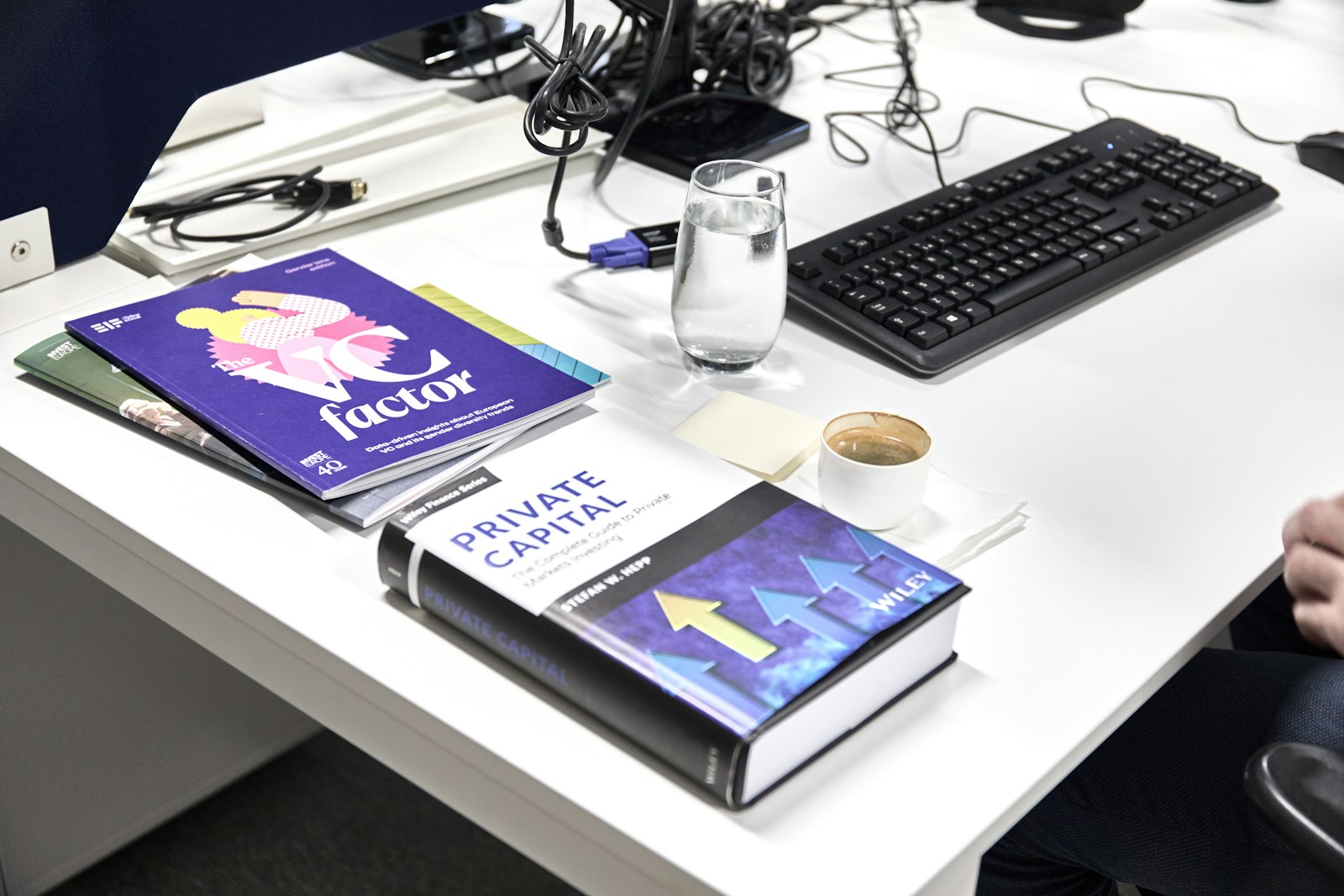Desk with books, keyboard, and coffee cup of coffee