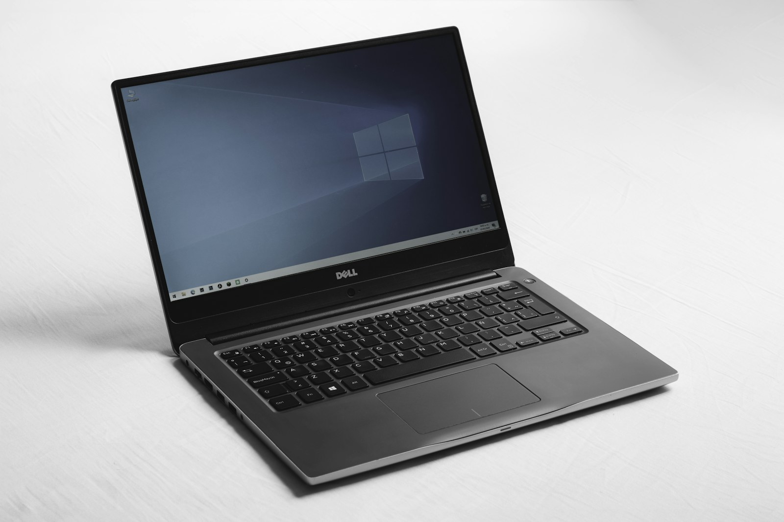 A Dell laptop with a blue desktop screen on a white surface