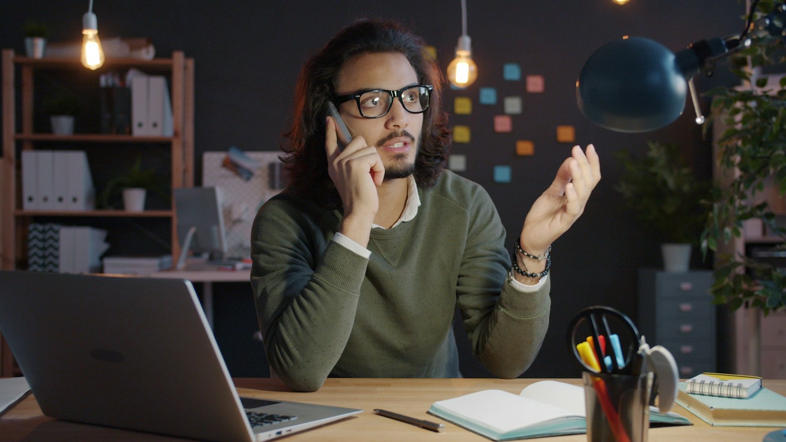 Man talking on phone at desk with laptop