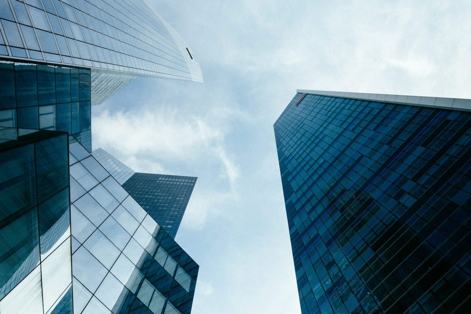 Low angle view of glass skyscrapers reaching toward a bright blue sky