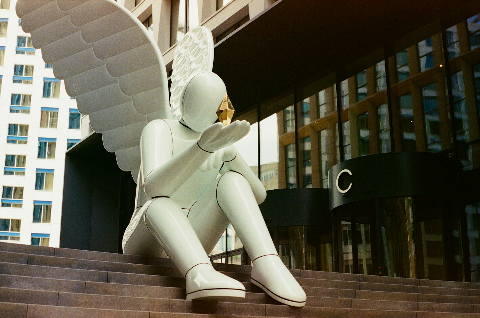 Modern white angel statue sits on steps with golden object