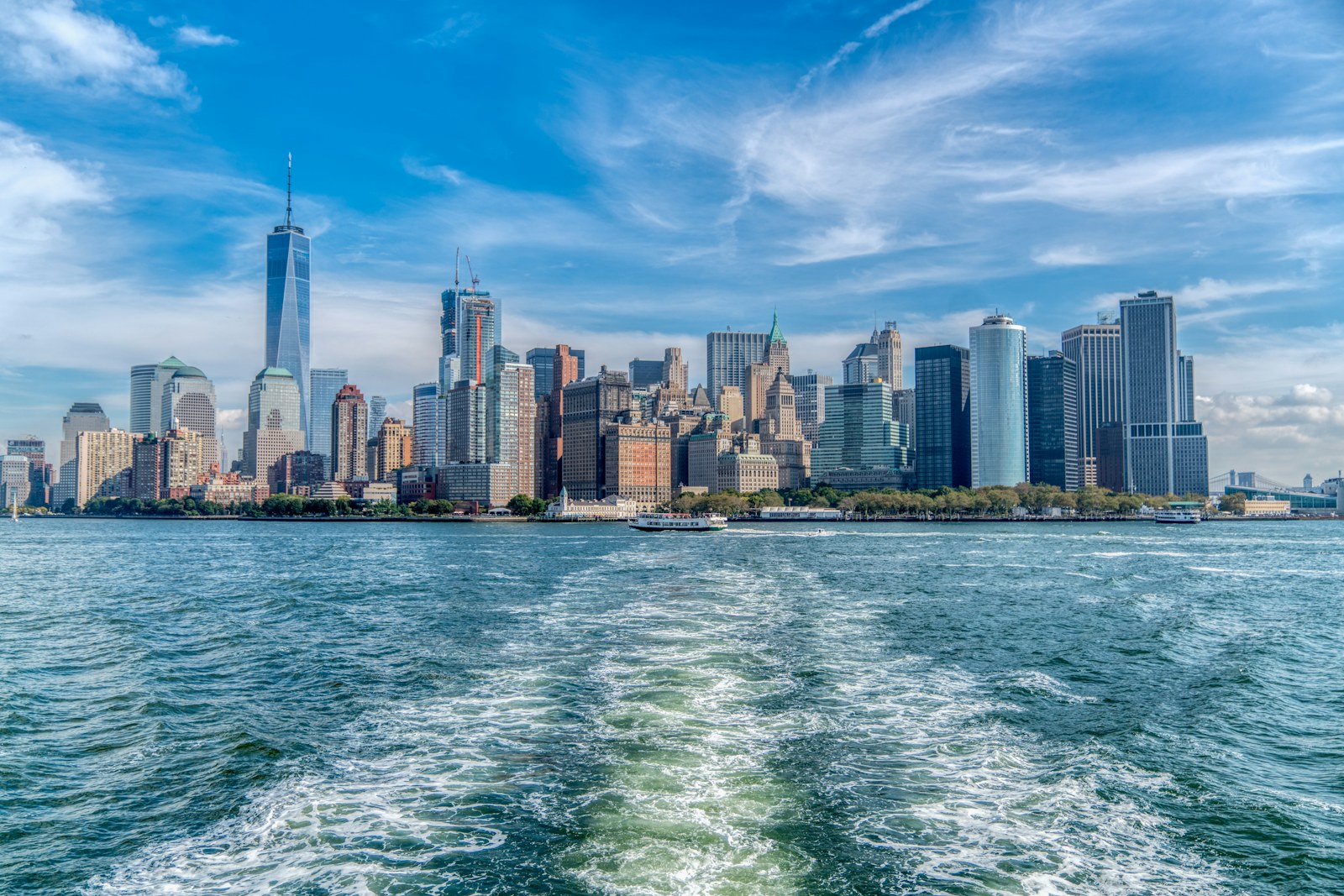 city skyline across body of water under blue and white sunny cloudy sky during daytime