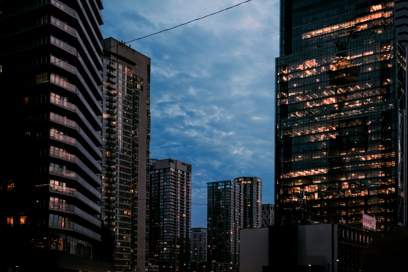 Modern skyscrapers with glowing office windows against a deep blue evening sky