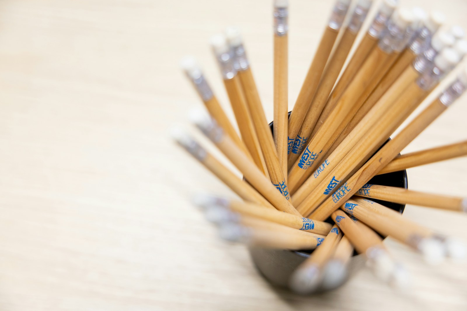 A cup filled with lots of pencils on top of a table