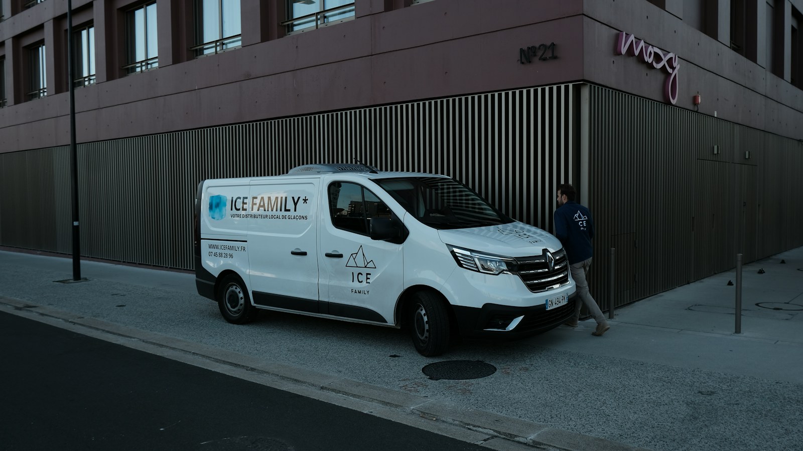 A white van parked next to a tall building