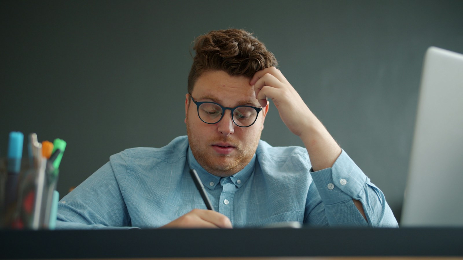 Man with glasses looking stressed at desk