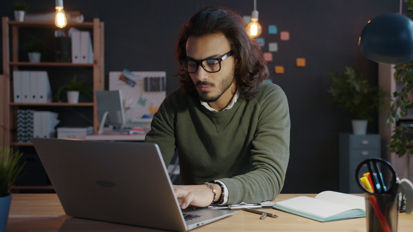 Man working on laptop in dimly lit office
